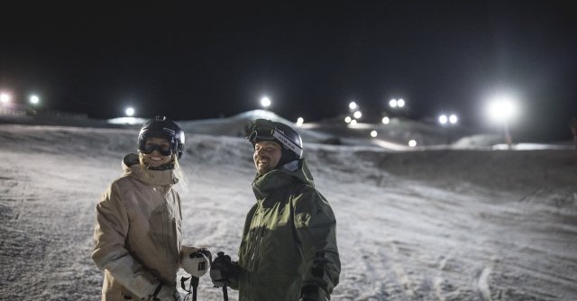 Skiiers on snow field at night